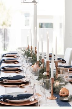 a dining table set with candles, plates and place settings for an elegant holiday dinner