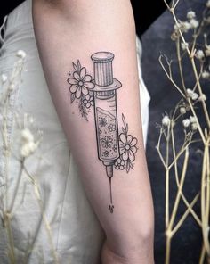 a woman's arm with a tattoo on it and flowers around the arm,