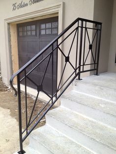 a set of stairs leading up to a garage door with an iron handrail and gate