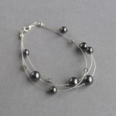 I have used Swarovski pearls and crystals to create this dark grey floating pearl bracelet. As pearls are timeless, these charcoal grey pearl bracelets make elegant gifts for a bride or her bridesmaids. The length of this black pearl multi-strand bracelet is 7.5 inches / 19cm. Each 3 strand bracelet has been completed with a silver plated lobster clasp and a 1 inch extension chain to allow you to adjust your three strand bracelet to fit. Your illusion jewellery will arrive gift wrapped and ready to present as a gift or a treat to yourself. All of my items are carefully packaged to ensure they reach you safely. --------------------- Matching items available --------------------- Dark grey floating pearl necklace: https://www.etsy.com/listing/687965272 Dark grey pearl studs: https://www.etsy Black Pearl Jewelry, Three Strand Bracelet, Black Pearl Bracelet, Floating Pearl Necklace, Black Pearl Earrings, Pearl Jewelry Gift, Jewelry King, Pearl Jewelry Sets, Multi Strand Bracelet