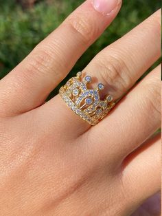 a woman's hand wearing a gold ring with blue and white stones on it