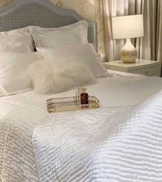 a bed with white sheets and pillows on top of it next to a night stand