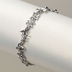 a silver bracelet on top of a white napkin with an arrow and cross charm in the middle