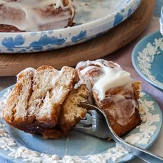 a piece of cinnamon roll on a plate with a fork in it and another slice missing