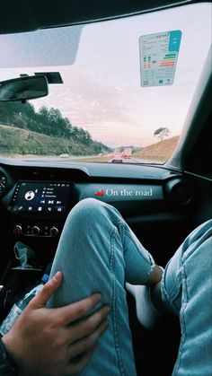 a person sitting in the driver's seat of a car with their feet on the dashboard