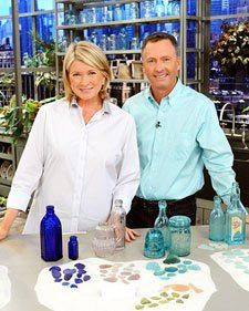 two people standing behind a table with vases and bottles on it