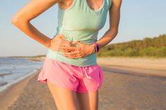 a woman standing on the beach with her stomach exposed