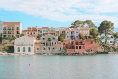 a row of houses sitting on top of a hill next to the ocean in front of some buildings