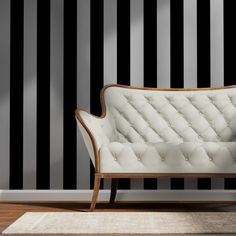 a white couch sitting on top of a wooden floor next to a black and white striped wall