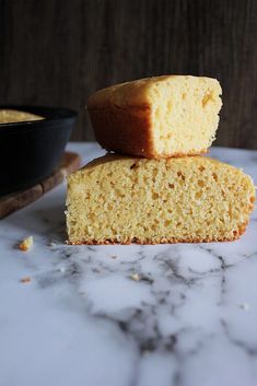 two pieces of cake sitting on top of a marble counter next to a black bowl