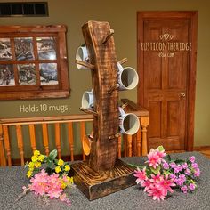 a wooden stand with coffee cups on it and flowers in front of the cup holder