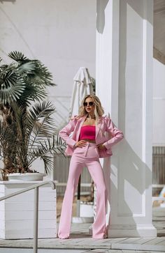 a woman in pink is posing for the camera while wearing sunglasses and a pink suit