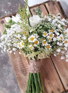 a bouquet of daisies and other flowers in a vase on a wooden table top