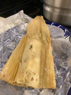 a tamales sitting on top of an ice covered plate next to a pot and pan