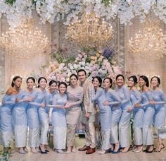 a group of women standing next to each other in front of a chandelier