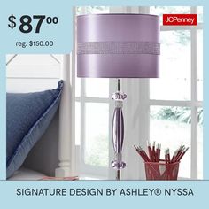 a purple lamp sitting on top of a table next to a pillow and pen holder