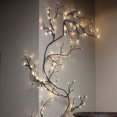 a metal tree with lights on it next to a wall