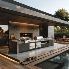 an outdoor kitchen and dining area next to a pool