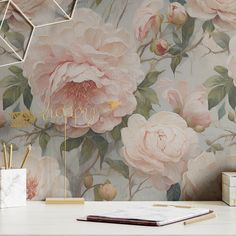 a desk with a notebook, pen and pencil holder on it next to a flower wallpaper