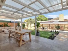 a covered patio with table, chairs and couches in the middle of an open area