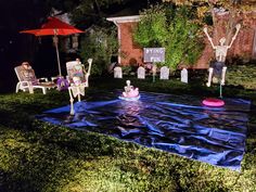 an outdoor area with lawn furniture and decorations on the grass at night, including chairs and umbrellas