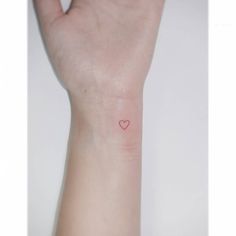 a small red heart tattoo on the wrist