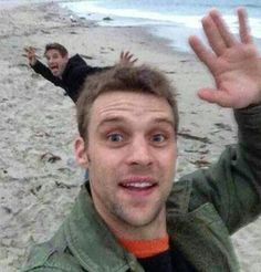 two men are on the beach with their hands in the air and one is waving