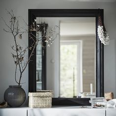 a mirror sitting on top of a dresser next to a vase