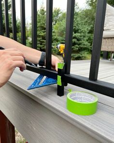 a person is measuring the width of a deck railing with tape on it while another hand uses a ruler to measure the edge