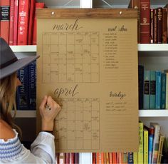 a woman is writing on a bulletin board in front of bookshelves full of books