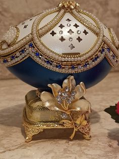 a blue and white decorative object sitting on top of a marble table next to a red rose