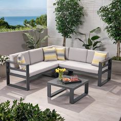 a couch and table sitting on top of a patio next to a wall with plants