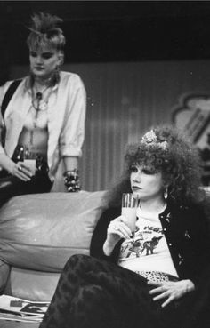 black and white photograph of two women sitting on a couch, one holding a drink