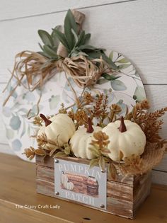 a wooden box filled with white pumpkins sitting on top of a table next to a sign