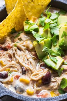 a bowl of chicken tortilla soup with avocado and cilantro