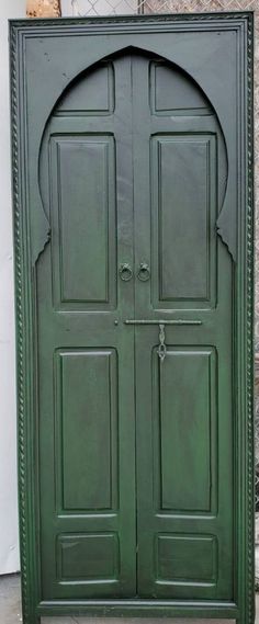 an ornate green door with two arched doors