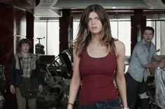 a woman in a red tank top is walking through a room with plastic covering the walls