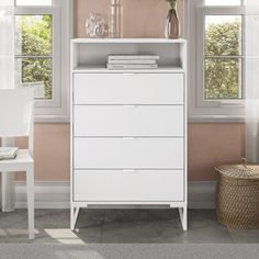 a white cabinet sitting in front of two windows next to a table with flowers on it