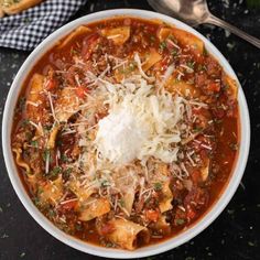 a white bowl filled with pasta and cheese on top of a black table next to bread