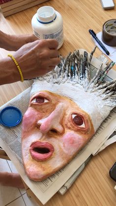 a person is making a mask out of paper and paintbrushes on the table