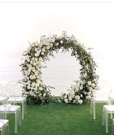 an outdoor ceremony set up with white flowers and greenery on the grass by the water