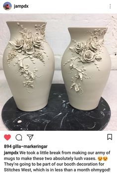 two white vases sitting on top of a table