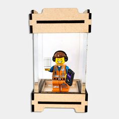 a lego man is in a glass case holding a cell phone and wearing an orange vest