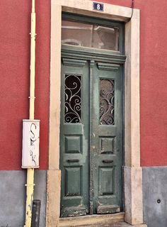 an old green door on the side of a red building