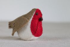 a small red and white bird sitting on top of a table