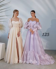 two women standing next to each other wearing dresses with ruffles and long sleeves