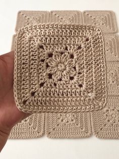 a hand is holding a crocheted square