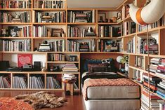 a bookshelf filled with lots of books next to a dog laying on the floor