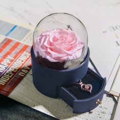 a pink rose in a blue box on top of a table