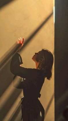 a woman is holding an object in her hand and looking up at the light coming through it